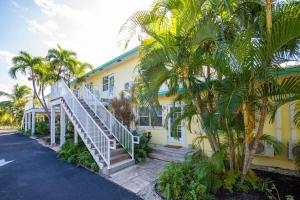 una casa gialla con palme di fronte di Snug Harbour View Condo #4 a George Town