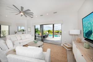 a living room with white furniture and a large tv at Mahogany Villa 2-A / 4BR 