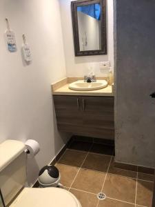 een badkamer met een wastafel, een toilet en een spiegel bij Comodo y central Apartamento -El poblado- Aguacatala in Medellín