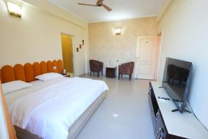 ein Schlafzimmer mit einem großen Bett und einem Flachbild-TV in der Unterkunft DESIRE Service Apartments- CyberCity in Gurgaon