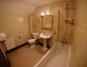 a bathroom with a sink and a toilet and a tub at The Crown Inn in Horsted Keynes