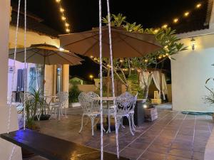 une terrasse avec une table, des chaises et des parasols dans l'établissement Suria 3 Sepang with private pool, à Sungai Pelik