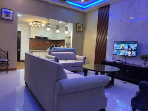 a living room with couches and a table and a tv at Suria 3 Sepang with private pool in Sungai Pelik