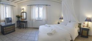 a bedroom with a white bed and a tv at Zephyros in Paraga