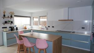a kitchen with blue cabinets and pink chairs at Casa nueva a pie de la Sierra de Guadarrama in Moralzarzal