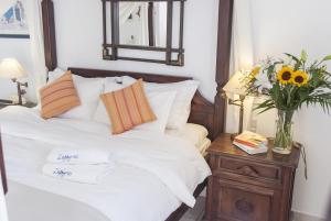 a bed with white sheets and a vase of flowers on a table at Zephyros in Paraga