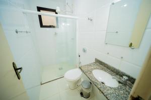 uma casa de banho com um lavatório, um WC e um espelho. em Joao Meira Apartments em Guarapari