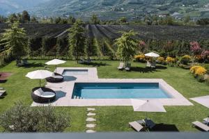 una piscina en medio de un patio con sombrillas en Auhof en Merano