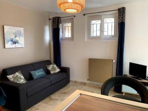 uma sala de estar com um sofá preto e uma televisão em Chez ALYS - Appartement Sarlat em Sarlat-la-Canéda