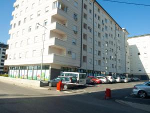 un gran edificio con coches estacionados en un estacionamiento en Apartman Valerija, en Doboj