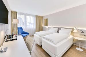 NH Weinheim في فاينهايم: غرفة بالفندق سرير ابيض وكرسي ازرق