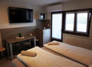 a room with two beds and a table and a tv at Kukorica Csárda Apartman 2 in Balatonújlak