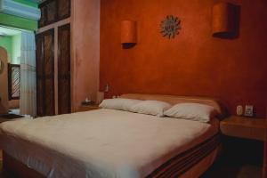 een slaapkamer met een groot bed met witte lakens bij Casabu in Zihuatanejo