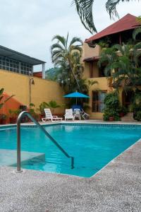 a swimming pool in front of a building at Casabu in Zihuatanejo