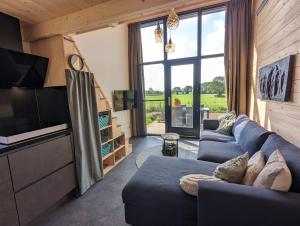 a living room with a blue couch and a large window at Klavertje 4 in Middelaar