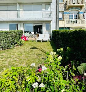 een tuin met twee stoelen en bloemen voor een huis bij Le Touquet Beach, Front de Mer in Le Touquet-Paris-Plage