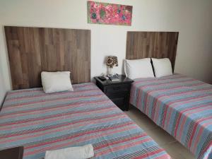 a room with two beds and a night stand with a bedskirts at HOSPEDAJE MAGNOLIAS MERIDA in Mérida