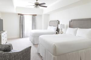 a white bedroom with a bed and a chair at Reunion Resort & Golf Club in Kissimmee
