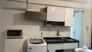 a small kitchen with a stove and a microwave at Apartamento central 2B in Montes Claros