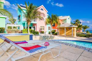 a chaise lounge next to a swimming pool with houses at Cayman Paradise Villa #1 in Sand Bluff