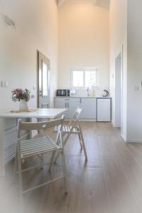 a white kitchen with a table and two chairs at Gal Ba'Har גל בהר in El-Rom
