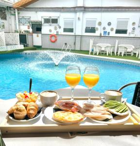 a tray of food and two glasses of wine next to a pool at Hostal Avenida Andalucia in Seville