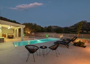 a patio with chairs and a swimming pool at night at Mary's Villa in Levkóyia