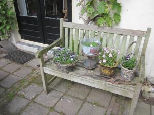 a wooden bench with baskets of flowers on it at B&B Beatrix in Beilen