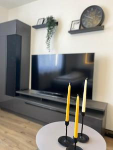 twee kaarsen op een tafel in een woonkamer met een klok bij Black&Yellow Designer Apartment Bielefeld in Bielefeld