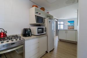 eine Küche mit einem Herd, einer Mikrowelle und einem Kühlschrank in der Unterkunft Sossego frente mar com vista para a ilha CCA201 in Florianópolis
