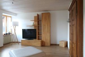 een woonkamer met een televisie en een houten kast bij Appartement de vacances in Saulcy