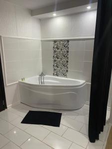 a white tub in a bathroom with a black shower at Karra Hotels in Voluntari