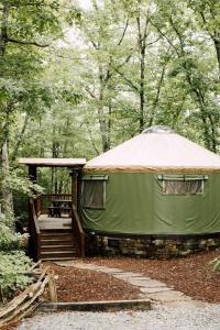 une tente verte avec une terrasse dans les bois dans l'établissement Tuckaseegee @ Sky Ridge Yurts, à Bryson City