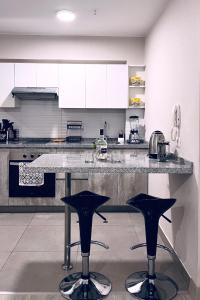a kitchen with black stools in the middle of a counter at Loft céntrico San borja - San Isidro in Lima