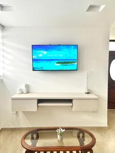 sala de estar con TV en una pared blanca en Suite Los Sauces, en Ibarra