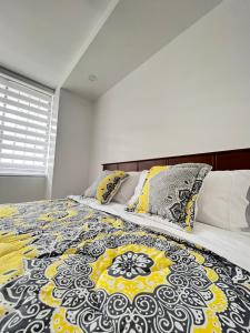 a bedroom with a bed with a black and yellow blanket at Suite Los Sauces in Ibarra