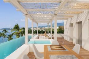 une villa avec une piscine et une femme assise sur une table dans l'établissement Casa Las Palmas - Condos by the Beach with Rooftop Pool, à Bucerías