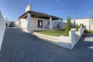 uma pequena casa branca com um telhado numa rua em Casa das Chaminés em Santo António do Baldio