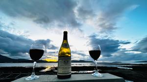 BreakishCarnmhor, Isle of Skye - Stunning 242 year old cottage on its own sea shore!的桌上有一瓶酒和两个酒杯