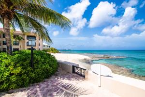 una playa con un edificio, palmeras y el océano en Georgetown Villas #201, en George Town