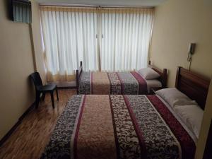 una habitación de hotel con 2 camas y una silla en HOSTAL EL CONFORT QUITO NORTE, en Quito