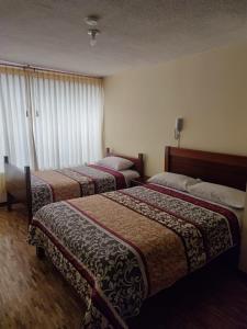 Habitación de hotel con 2 camas y ventana en HOSTAL EL CONFORT QUITO NORTE, en Quito