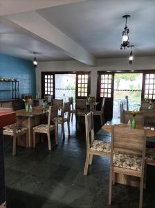 a restaurant with wooden tables and chairs and windows at Pousada A Pérola in Rio de Contas