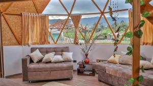 - un salon avec un canapé et une grande fenêtre dans l'établissement Magia Verde Glamping, à Tinjacá