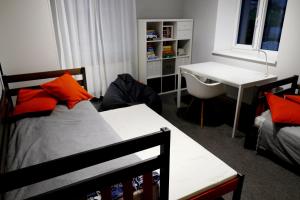 1 dormitorio con cama con almohadas de color naranja y escritorio en Kur palikt Salacgrīvā, en Salacgrīva