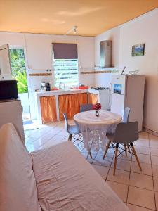 a kitchen with a table and chairs in a room at Maison d'une chambre avec piscine partagee terrasse amenagee et wifi a Petit Bourg in Petit-Bourg