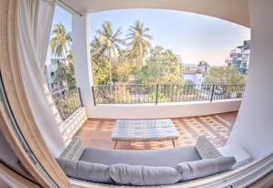 Cette chambre dispose d'un canapé et d'un balcon avec des palmiers. dans l'établissement Estadios Suites - Only 3 Blocks to Beach, à Bucerías