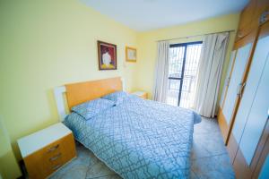 a bedroom with a blue bed and a window at Edificio Martha Schwantz in Guarapari