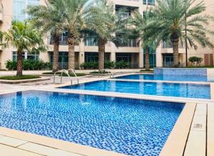 a large swimming pool with palm trees in front of a building at Panoramic Burj Khalifa View Apt Downtown Dubai in Dubai