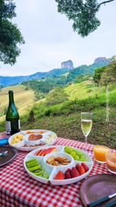 uma mesa com pratos de comida e um copo de vinho em Cabanas Bela Vista em São Bento do Sapucaí
